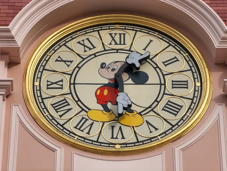 A clock with Roman numerals and Mickey Mouse whose arms are the clock hands, at Disneyland Paris